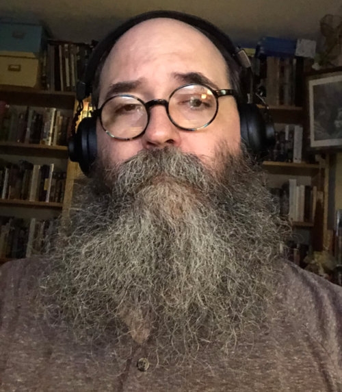 Selfie, in the study, without smile, with wild quarantine beard.